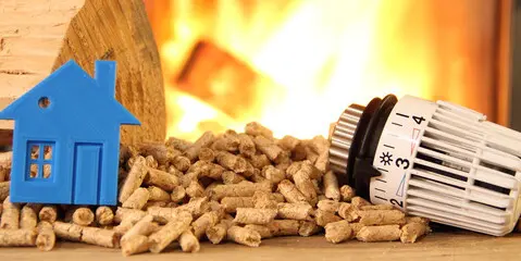 Pellets de bois avec en fond le feu de cheminé et une petite maison bleu